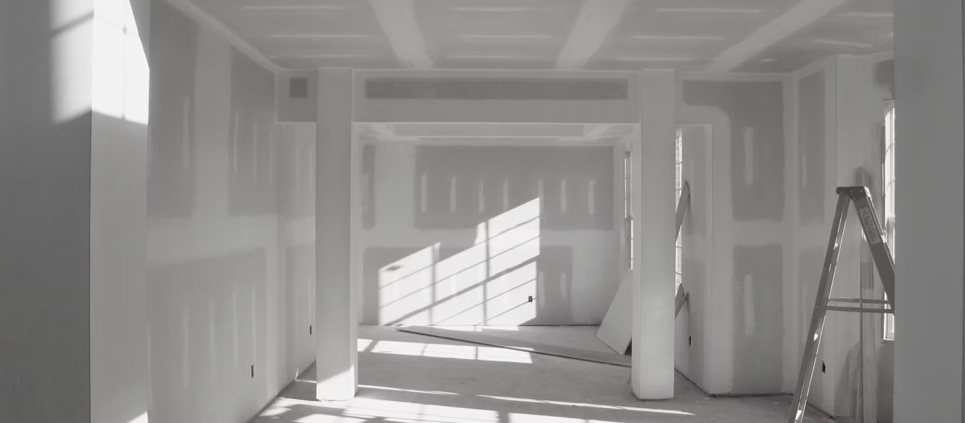 A finished drywall room with smooth walls, crisp corners, and sunlight raking across the surface.