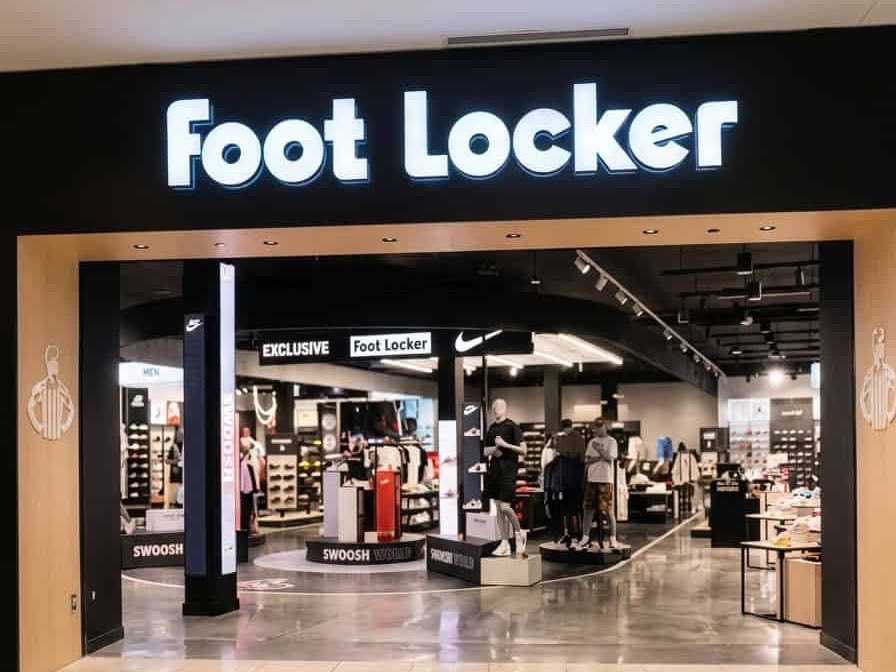 The Foot Locker storefront in Peabody, Massachusetts — an illuminated sign set into a finished black bulkhead above the open shopfront, with the sales floor visible beyond.