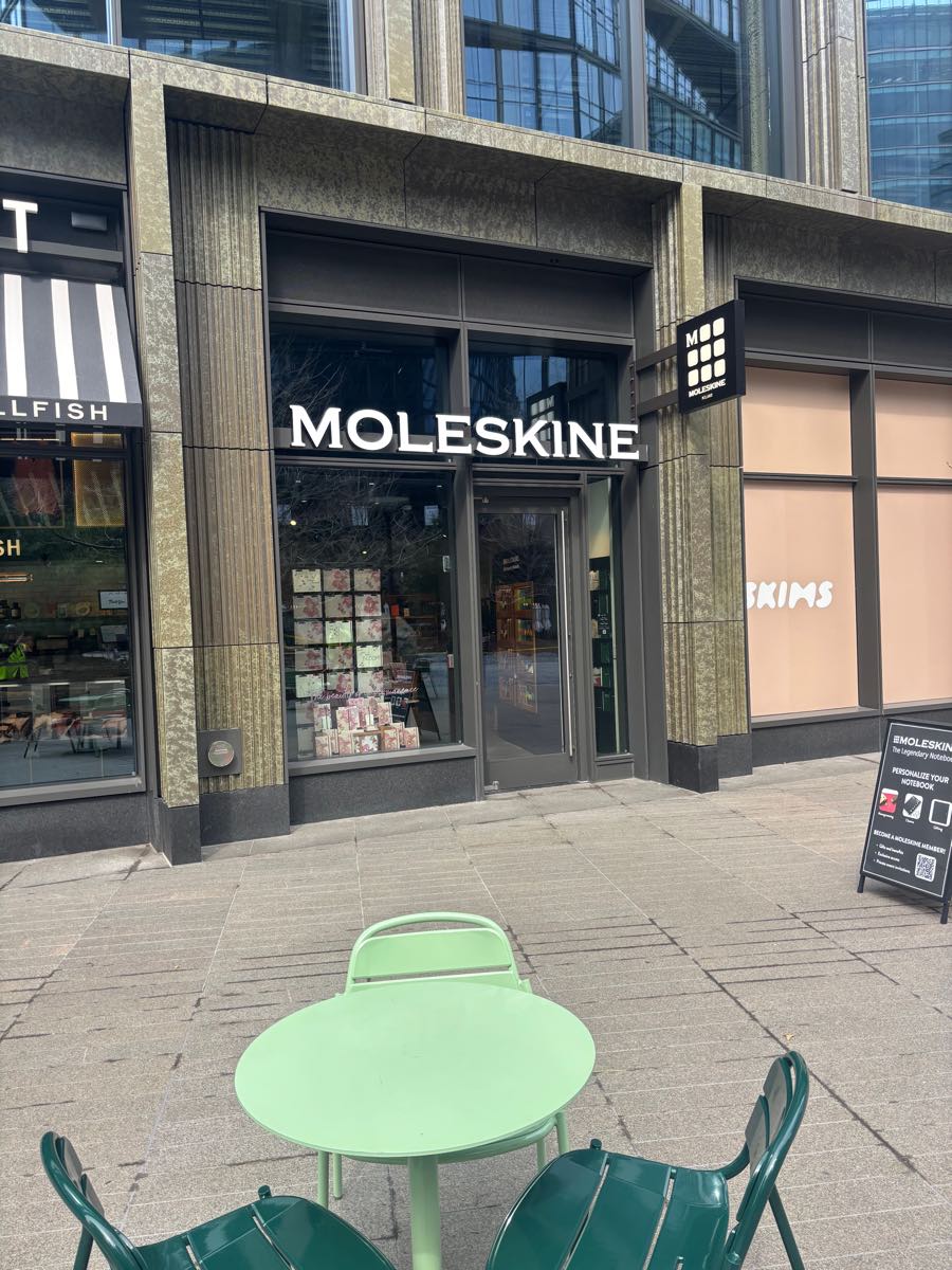 The Moleskine store on Harbor Way in Boston's Seaport District, with illuminated signage above a finished display window.