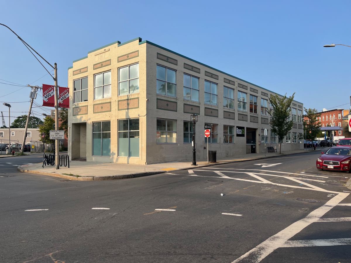 The Roca building at Park Street in Chelsea, Massachusetts — a two-story brick corner property with tall storefront windows and the Roca sign above the ground-floor entrance.